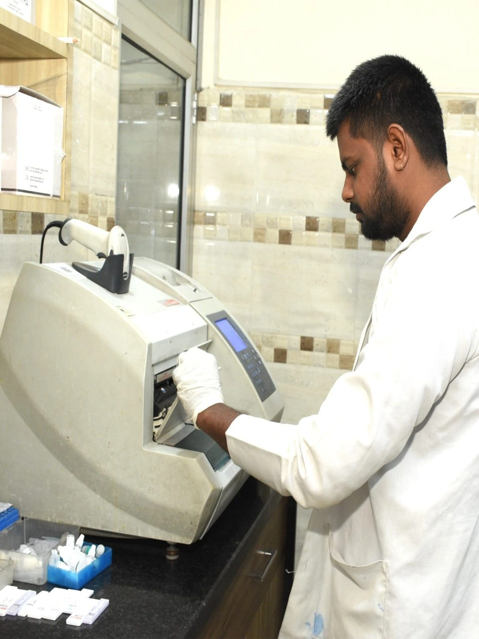 Lab technician in protective gear performing diagnostic sample preparation at Dr. Sudeep's Pathology.